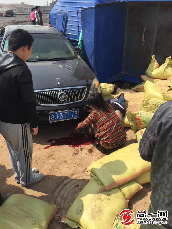 另一人被撞伤,躺在掉下的一堆饲料上,流了一地血.市民杨先生供图